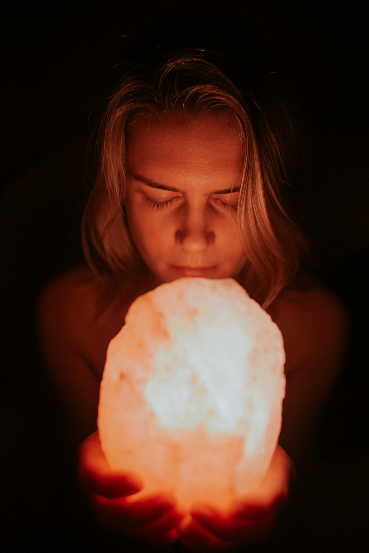 Person holding a glowing pink Himalayan salt lamp