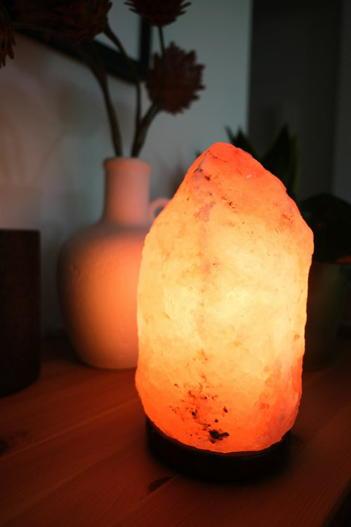 Himalayan salt lamp glowing warm amber on a wooden surface